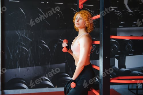 Preview: Close up of sporty woman lifting dumbbell in gym.