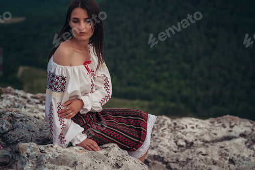 Preview: Atractive woman in traditional romanian costume on mountain green blurred background