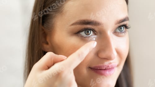 Preview: Young lady wearing contact eye lenses, close up