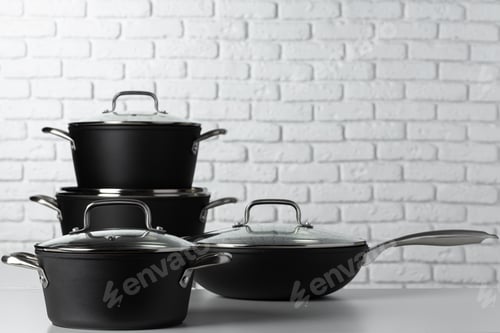 Preview: Set of cookware on table against white brick wall