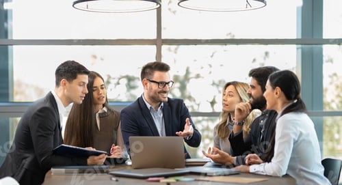 Preview: Proud business leader presenting results on laptop to team in modern office