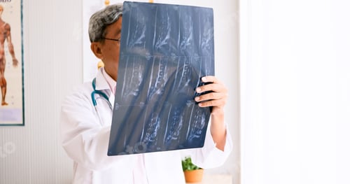 Preview: Doctor analysing diagnosis result on x-ray film in hospital room.