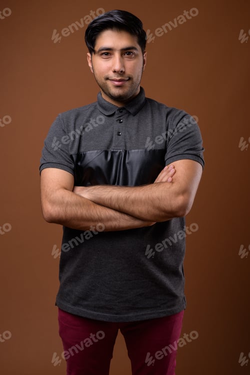 Preview: Studio shot of young handsome Iranian man against brown backgrou