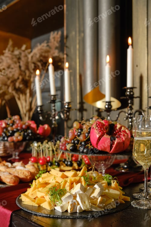 Preview: Elegant dining table set with cheese, fruits, and candles for a festive evening gathering