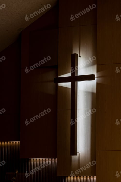 Preview: Vertical shot of a wooden cross attached to a wall with lights underneath.
