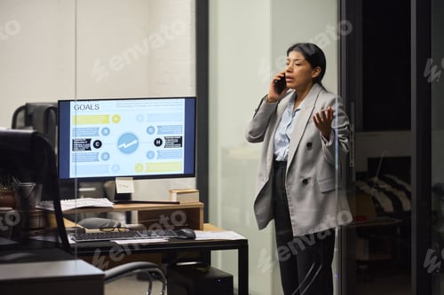 Preview: Latin Woman Talking on Smartphone While Working in Office