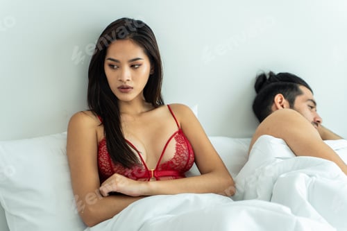 Preview: Attractive young couple lying on bed with painful after fight argument.