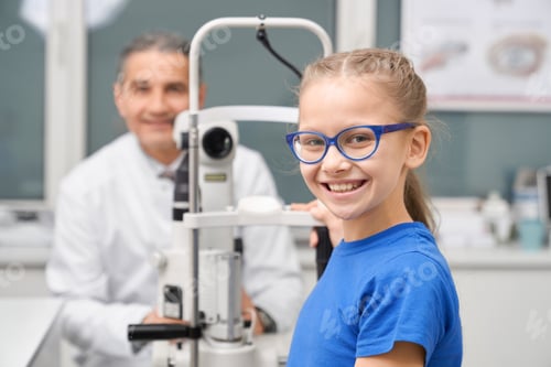 Preview: Teenage girl in blue glasses posing with doctor in clinic