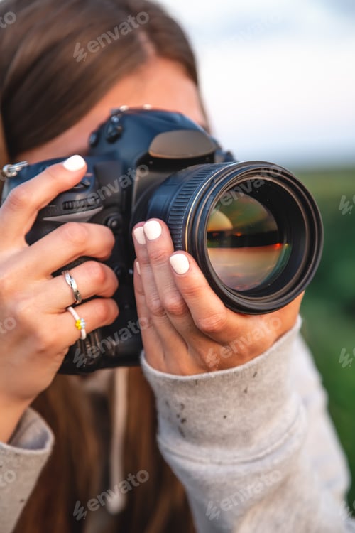 Preview: A young woman with a professional camera takes a photo in nature.