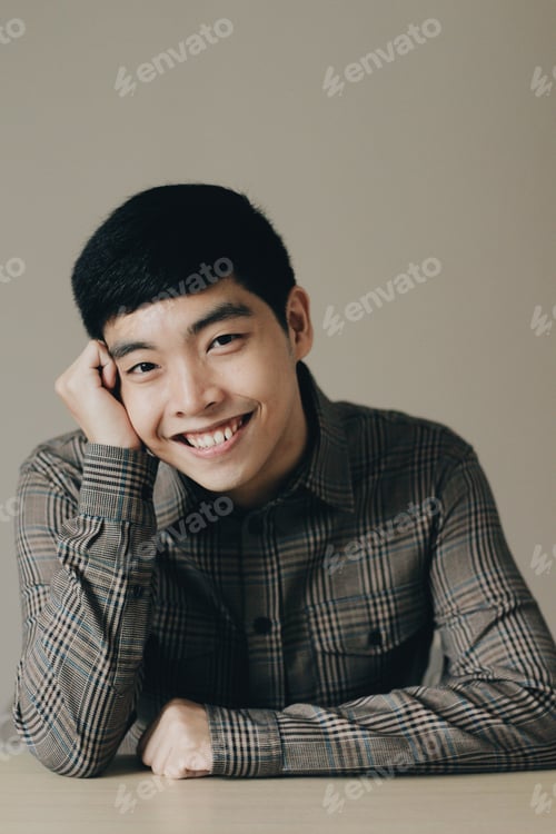 Preview: Closeup vertical portrait of a cute happy Asian man leaning his head into his hand