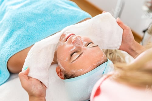 Preview: Beautician therapist applying face treatment in beauty salon to young woman.