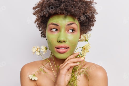 Preview: Spa beauty treatments and wellbeing concept. Afro American woman applies natural green mask made of