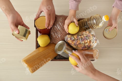 Preview: Volunteers taking food out of donation box on table, top view