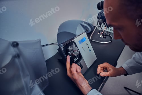 Preview: Expirienced watchmaker is doing engraving for custmer's watch using special tool at his workshop