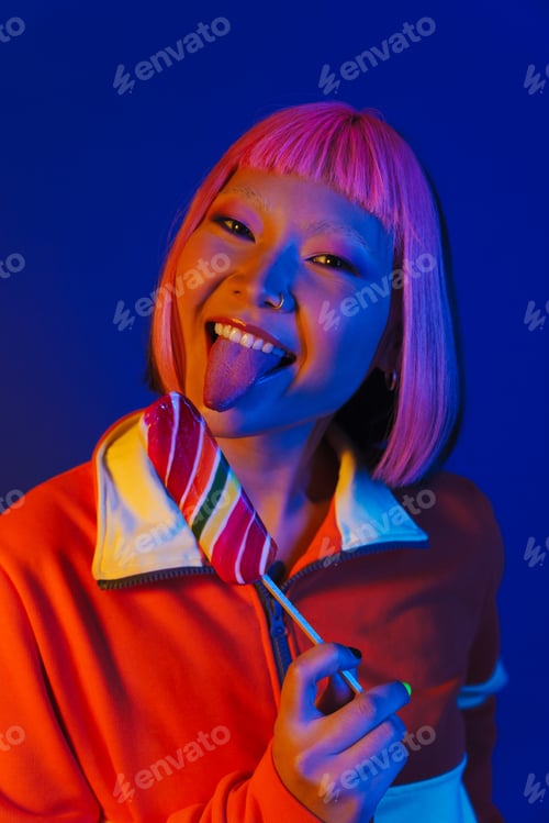 Preview: Asian girl with pink hair making fun while eating ice cream