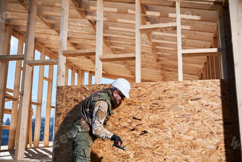 Preview: Carpenter hammering nail into OSB panel while building wooden frame house.