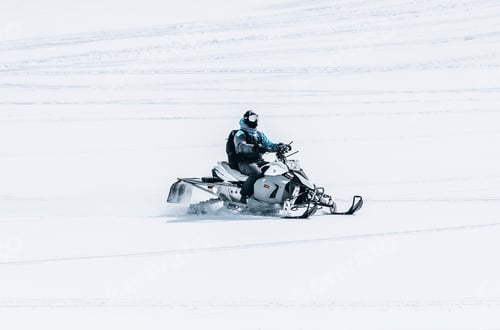 Preview: Male riding a snowmobile in a large snowy field