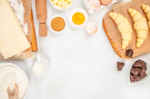 Preview: Raw Croissants with Baking Ingredients and Chocolate on White Background