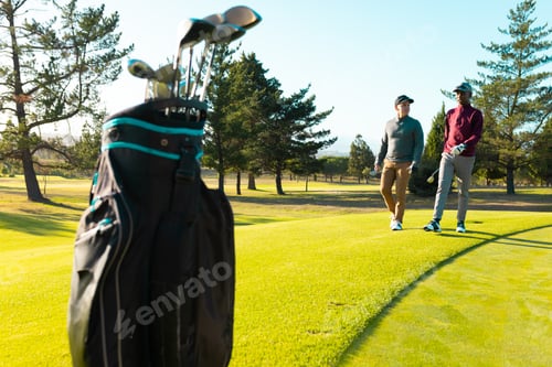Preview: Golf clubs in bag and multiracial young male friends walking at golf course in summer, copy space