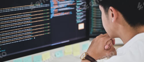 Preview: A male programmer sits and watches the code on a computer monitor to verify the program's execution.