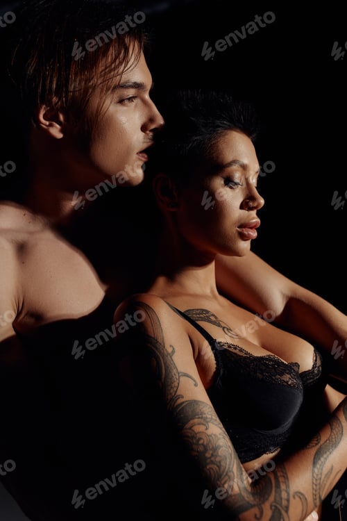 Preview: side view of tattooed woman with sexy breast near shirtless man isolated on black