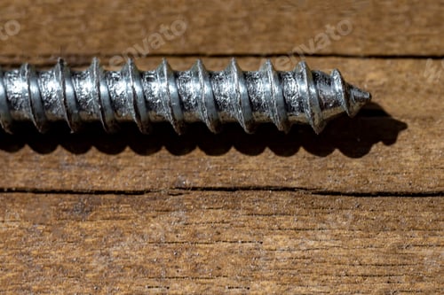 Preview: Macrophotography. Part of silver metal screw on brown wooden background. Copy space.