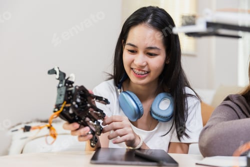 Preview: Happy two girl teen smile with braces students education stem hand robot model study in classroom.