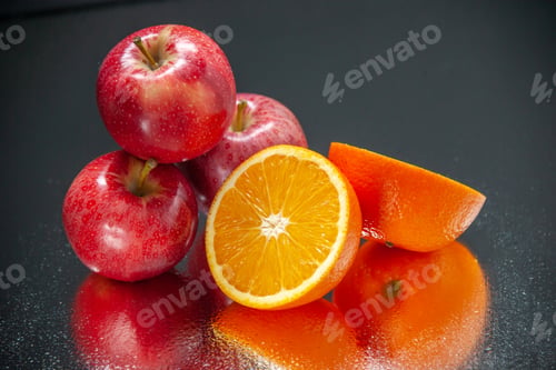 Preview: Top view of cut fresh oranges and red apples on light on black background with free space