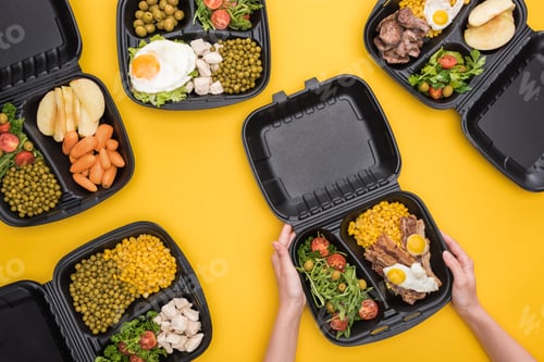 Preview: cropped view of woman holding eco package with corn, meat, fried eggs and salad isolated on yellow