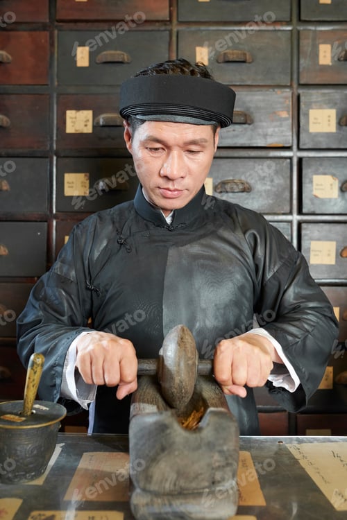 Preview: Traditional medicine practitioner grinding up dry herbs