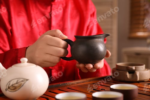 Preview: Master conducting traditional tea ceremony at table, closeup