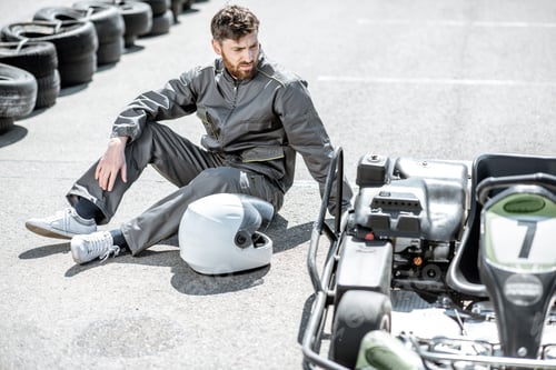 Preview: Man Sitting Next to Go-Kart on Track