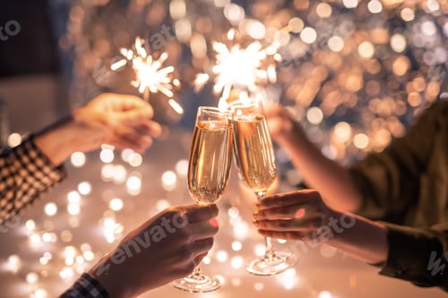 Preview: Hands of couple with flutes of champagne and their friends with bengal lights