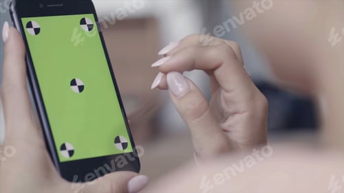 Preview: Close-up of young woman's hands with perfect manicure holding smartphone and sliding on the chroma
