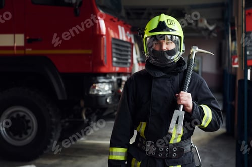 Preview: Male firefighter in protective uniform standing near truck