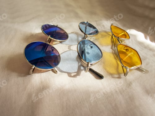 Preview: three pairs of sunglasses yellow, blue and mirror glasses on a linen background. colored glasses