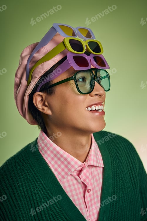 Preview: Stylish asian man showcases vibrant fashion in a green studio setting