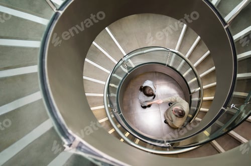 Preview: Business duo shake hands in a stairwell