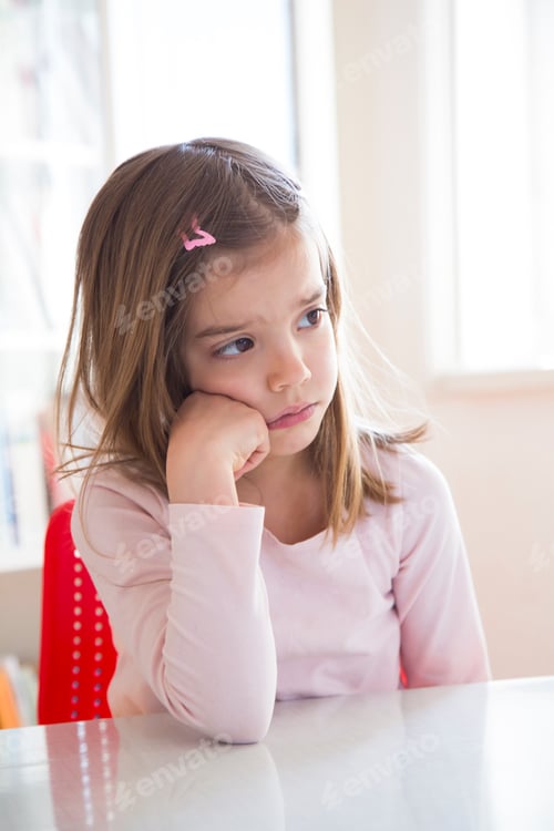 Preview: Portrait of sad little girl at table