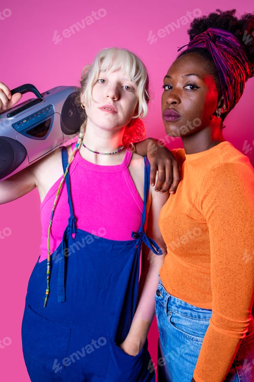 Preview: Two young diverse women holding boombox posing isolated confident