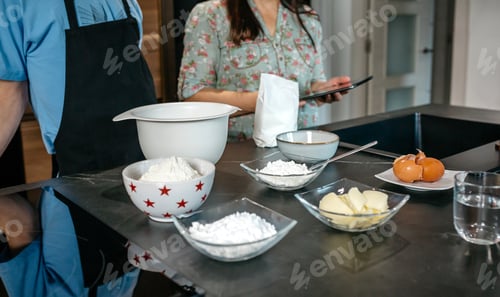 Preview: Unrecognizable mother and son preparing ingredients following online recipe on tablet