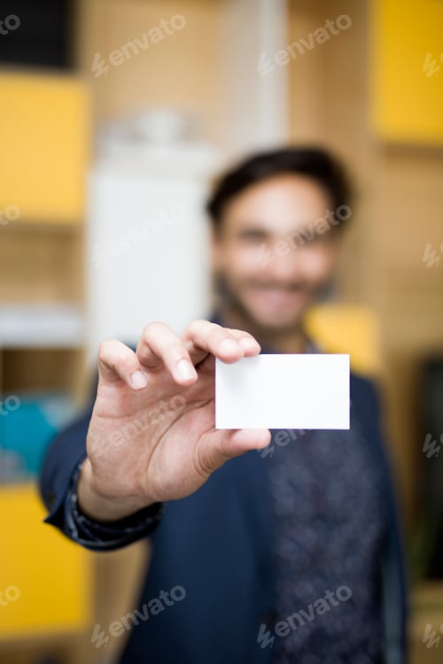 Preview: Businessman holding empty business card in front of camera