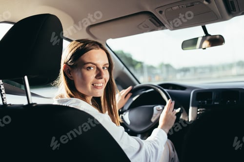 Preview: Portrait of a successful woman driving a car, smiling rejoicing and looking at the camera