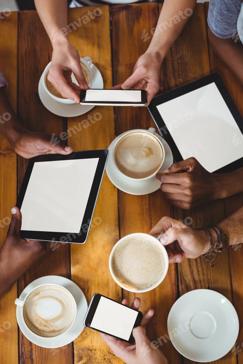 Preview: Group of friends using mobile phone while having cup of coffee