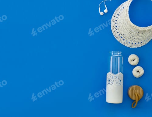 Preview: Overhead view of a white objects sun visor donuts earbuds and water bottle on a blue background