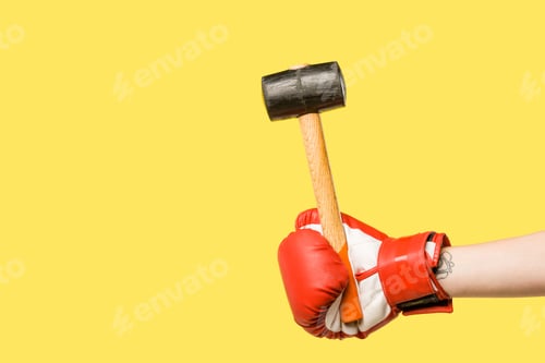 Preview: cropped shot of person in boxing glove holding hammer isolated on yellow