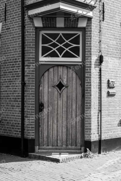 Preview: Exterior facade of a brick building featuring a window over a doorway with a wooden door