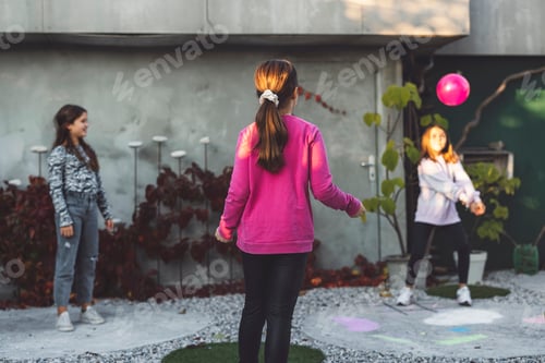 Preview: Three children playing in a garden. One girl in a pink sweater is facing away, while two others are