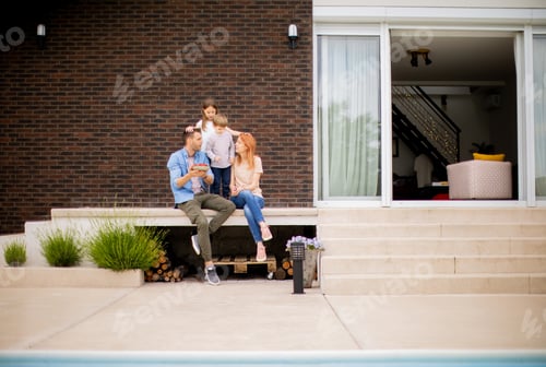 Preview: Family with a mother, father, son and daughter sitting outside on steps