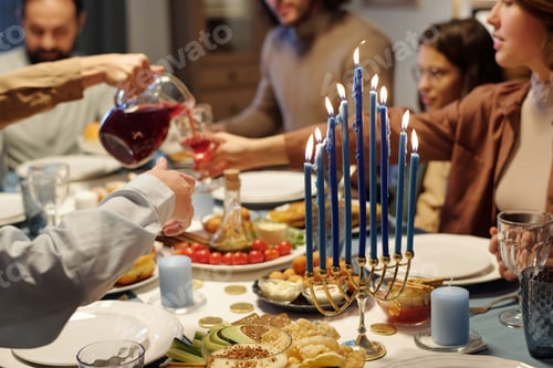 Preview: Focus on blue burning candles on menorah candlestick standing on table
